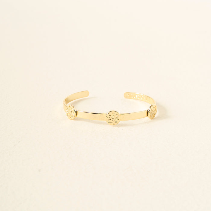 The Darling Effect's "You Are Compassionate" Skinny Stacker Bracelet is a 14k gold plated adjustable cuff with three round, textured medallions, elegantly displayed on a cream surface—an ideal gift-ready piece of jewelry.