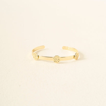 The Darling Effect's "You Are Compassionate" Skinny Stacker Bracelet is a 14k gold plated adjustable cuff with three round, textured medallions, elegantly displayed on a cream surface—an ideal gift-ready piece of jewelry.