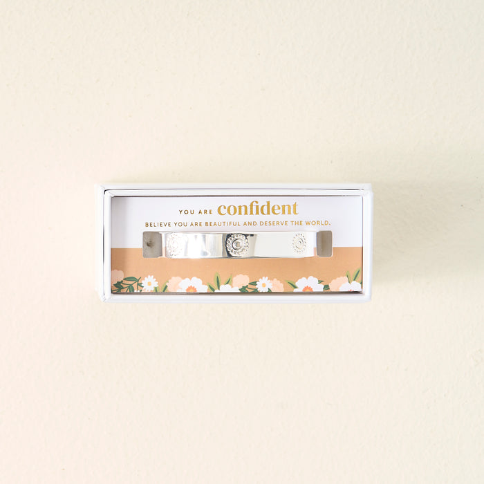 The Darling Effect's You Are Confident Trait Cuff Bracelet, crafted in sterling silver and engraved, comes boxed with a floral border and card that reads: You are confident. Believe you are beautiful and deserve the world—a meaningful gift.