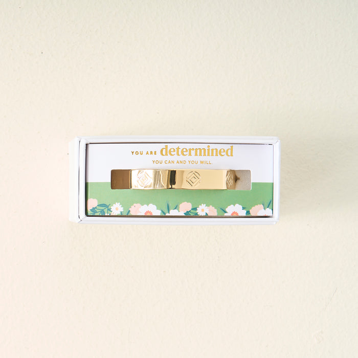 The Darling Effect's You Are Determined Cuff Bracelet comes boxed with the message "You are determined. You can and you will." on green floral packaging, making a meaningful gift set against a light beige background.