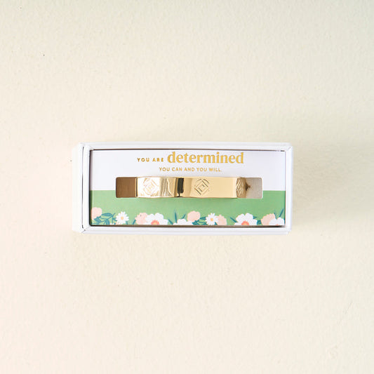 The Darling Effect's You Are Determined Cuff Bracelet comes boxed with the message "You are determined. You can and you will." on green floral packaging, making a meaningful gift set against a light beige background.