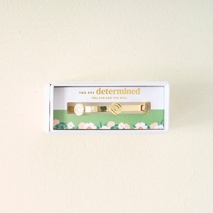 The Darling Effect’s You Are Determined Skinny Stacker Bracelet features two diamond-shaped designs, 14k gold plating, and comes gift-ready in a white box with a floral liner reading “You are determined. You can and you will.”.