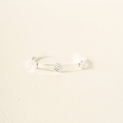 The Darling Effect’s "You Are Determined" Skinny Stacker Bracelet is a polished silver adjustable cuff with three diamond-shaped charms, shown on a cream background—an elegant, gift-ready accessory.