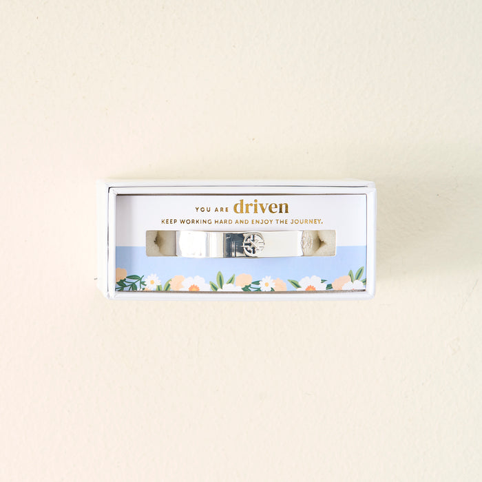 The Darling Effect's You Are Driven Cuff Bracelet is a sterling silver piece inscribed with "YOU ARE driven. KEEP WORKING HARD AND ENJOY THE JOURNEY," presented in a floral-bordered gift box—a meaningful gift.