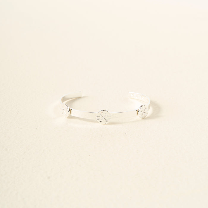 The Darling Effect’s You Are Driven Skinny Stacker Bracelet is an adjustable silver cuff with three engraved circular floral designs, displayed on a light cream background.