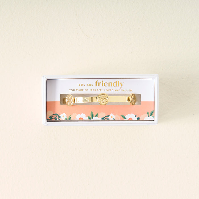 The Darling Effect You Are Friendly Skinny Stacker Bracelet, a 14k gold plated adjustable cuff, comes in a white floral box with a card that says, "You are friendly. You make others feel loved and valued." Perfect gift-ready jewelry.