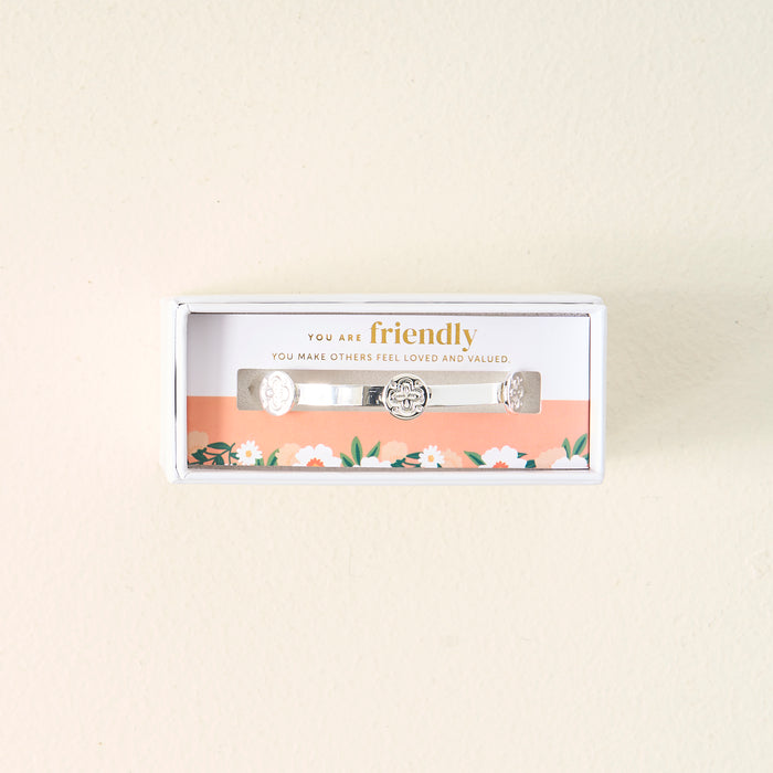 The Darling Effect’s You Are Friendly Skinny Stacker Bracelet comes in a white box with engraved details and a floral-accented insert that reads: “You are friendly. You make others feel loved and valued”—perfect for gifting.
