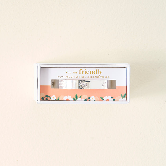 The Darling Effect’s You Are Friendly Trait Cuff Bracelet features sterling silver and comes in a white box with a floral design and the message "You are friendly. You make others feel loved and valued" printed inside—a thoughtful gift.