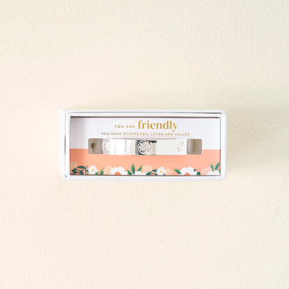 The Darling Effect’s You Are Friendly Trait Cuff Bracelet features sterling silver and comes in a white box with a floral design and the message "You are friendly. You make others feel loved and valued" printed inside—a thoughtful gift.
