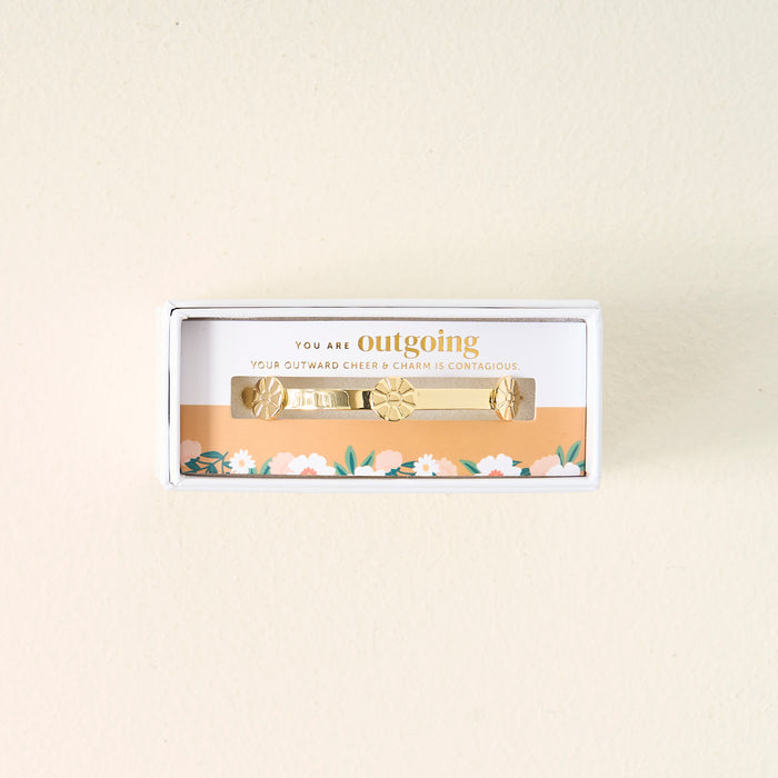 Gift-ready from The Darling Effect, the You Are Outgoing Skinny Stacker Bracelet is a 14k gold plated adjustable cuff in a box, delicately accented with florals and engraved: YOU ARE outgoing. YOUR OUTWARD CHEER & CHARM IS CONTAGIOUS.