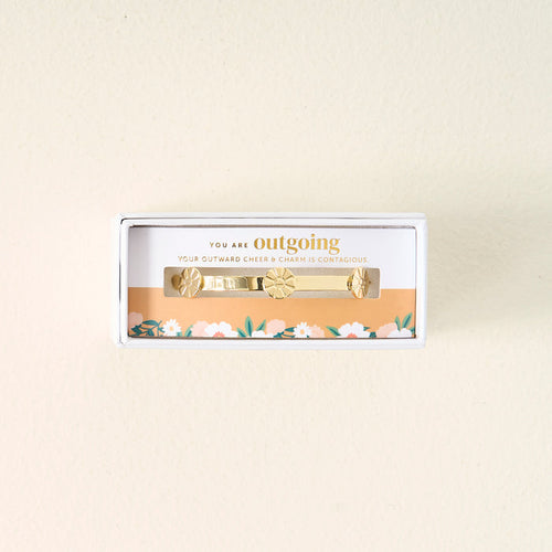 Gift-ready from The Darling Effect, the You Are Outgoing Skinny Stacker Bracelet is a 14k gold plated adjustable cuff in a box, delicately accented with florals and engraved: YOU ARE outgoing. YOUR OUTWARD CHEER & CHARM IS CONTAGIOUS.