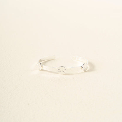 The Darling Effect's "You Are Outgoing" Skinny Stacker Bracelet is a gift-ready adjustable cuff with a sleek silver design and starburst engravings, displayed on an off-white background.