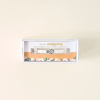 The Darling Effect's You Are Outgoing Skinny Stacker Bracelet is a 14k gold plated adjustable cuff with a central charm and two side charms, gift-ready in a box that says, "You are outgoing. Your outward cheer & charm is contagious.