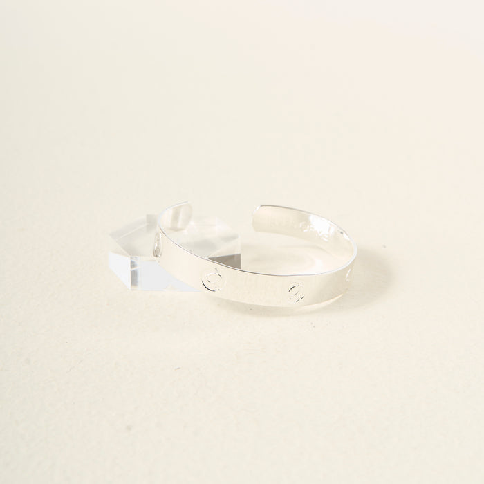 The Darling Effect’s "You Are Sassy" cuff bracelet, crafted in sterling silver with engraved circular designs and text, rests on a clear acrylic stand against a light cream background.