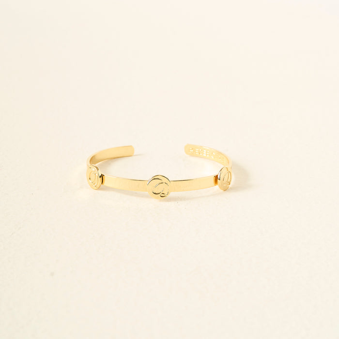 The Darling Effect’s You Are Sassy Skinny Stacker Bracelet is a 14k gold plated adjustable cuff with three round accents, shown on a textured light surface.