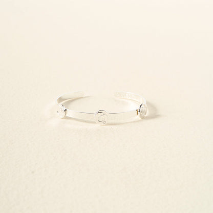 The Darling Effect's You Are Sassy Skinny Stacker Bracelet is a thin, silver adjustable cuff with three evenly spaced circular accents, shown on a neutral, light background.