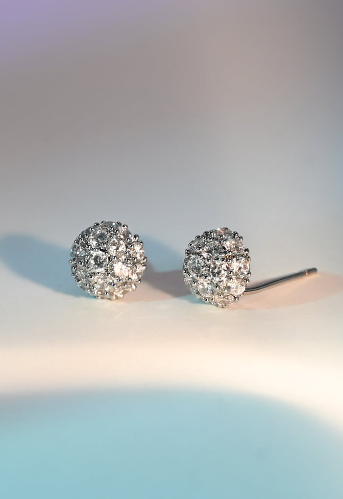 Pair of silver earrings with clear stones on a light background
