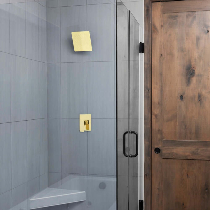 ZLINE 12 in. Oversized Bliss Shower Head in Polished Gold (BLS-H12-PG) in a glass shower enclosure, wooden door, and tiled walls.