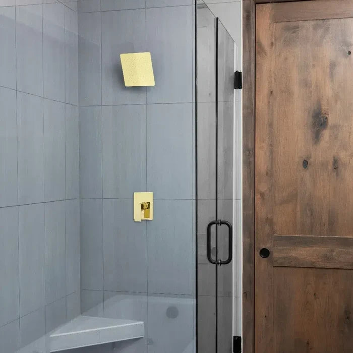 Bathroom with gray tiled wall, shower area with ZLINE 8 in. Bliss Shower Head in Polished Gold (BLS-H8-PG), and a wooden door.